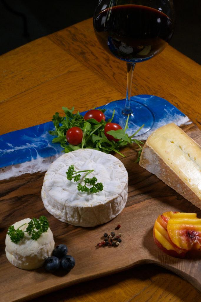 Camembert, fromages et vin rouge sur planche en bois et résine bleue Camembert, fromages et vin rouge sur planche en bois et résine bleue
