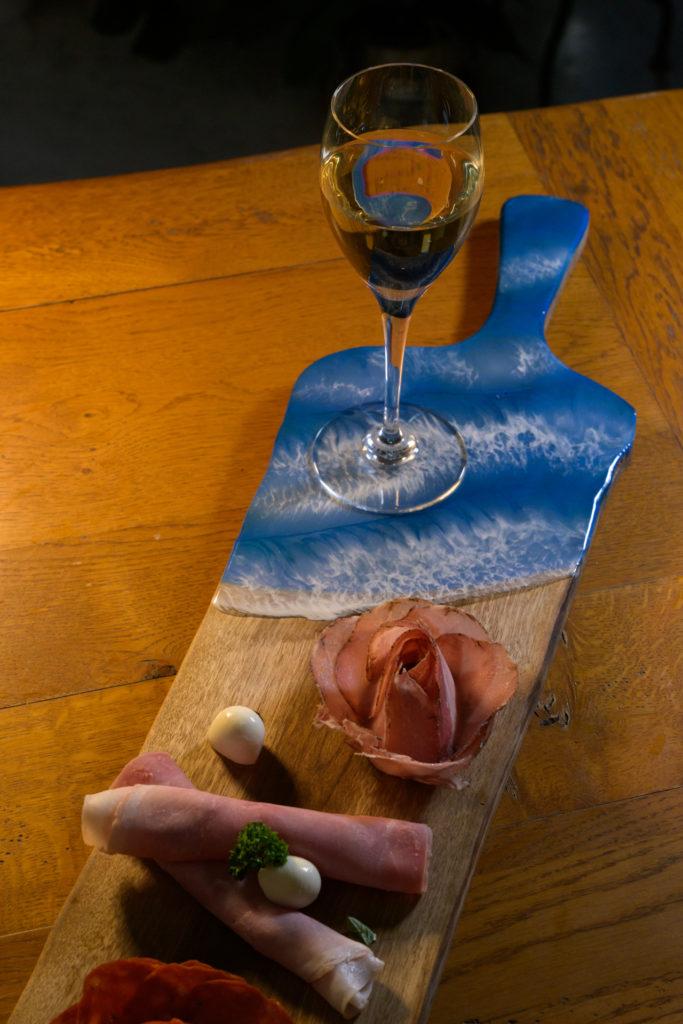 Charcuterie et vin blanc sur planche à manche en bois et résine Charcuterie et vin blanc sur planche à manche en bois et résine